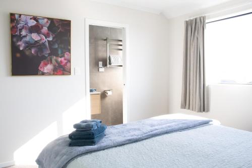 um quarto com uma cama com toalhas azuis em New cosy house, close to shoppong center em Hamilton