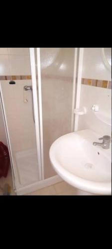 Un baño con lavabo blanco y ducha. en شط مريم, en Hammam Sousse