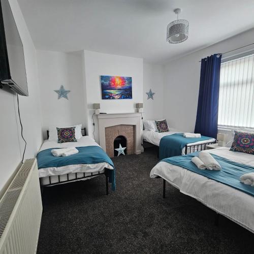 a room with two beds and a fireplace in it at Lyndhurst Terrace, Sunderland in Trimdon Grange