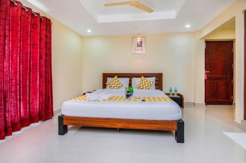 a bedroom with a large bed with red curtains at FabHotel Krishna Residency in Chennai