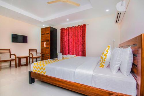 a bedroom with a large bed with a red curtain at FabHotel Krishna Residency in Chennai