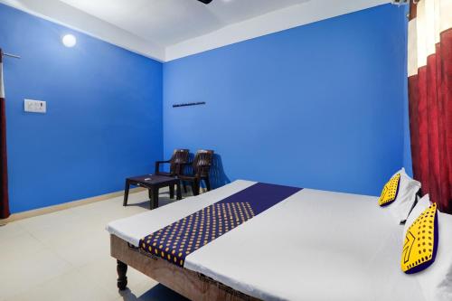 a bedroom with blue walls and a bed with chairs at SPOT ON New Modern Guest House in Varanasi