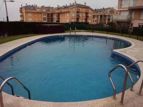 uma grande piscina com água azul em frente a um edifício em Apartamento Playa Catedrales con Piscina em Barreiros
