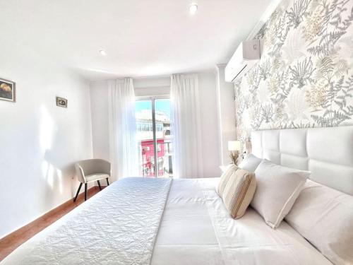 a white bedroom with a large bed and a window at LaFrenchTouch - Céntrico y moderno cerca del tren in Benalmádena