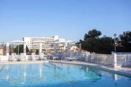 a swimming pool with chairs and a building in the background at BQ Apolo Hotel in Can Pastilla