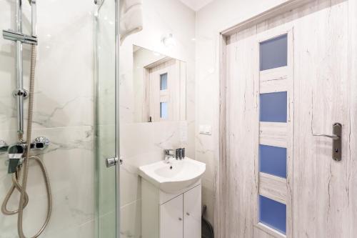 a white bathroom with a sink and a shower at Nadmorski apartament XXIV by Holiday&Sun in Grzybowo