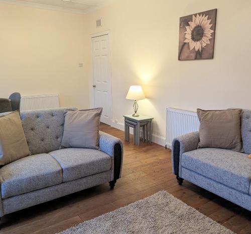 sala de estar con 2 sofás y mesa con lámpara en Aberfeldy Retreat, en Aberfeldy