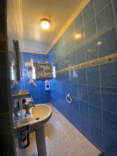 a bathroom with a sink and a blue tiled wall at villa à souiriya kdima in Safi