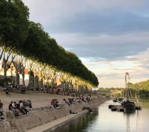 a group of people sitting on a wall next to a river at Appartement centre d'Orléans en bord de Loire in Orléans
