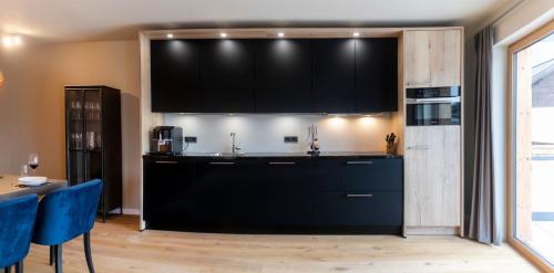 a kitchen with black cabinets and blue chairs at Residenz Illyrica Tirol in Westendorf