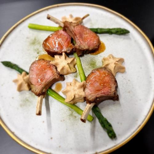 a white plate with three pieces of meat and asparagus at Hotel Nuovo in Garlate