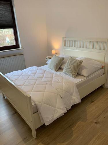 een groot wit bed in een slaapkamer met een raam bij Stilvolle Wohnung mit Balkon & Parkplätzen in Bremen
