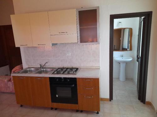 a kitchen with a sink and a stove top oven at La Macciona in Aglientu