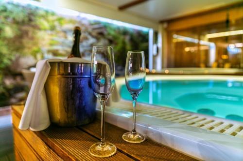 two wine glasses sitting on a table next to a pool at Kontakt Wellness Hotel in Tatranská Lomnica