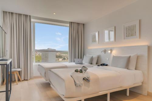 a white bedroom with a large bed and a large window at Pestana Tanger - City Center Hotel Suites & Apartments in Tangier