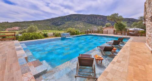 uma piscina com cadeiras e montanhas ao fundo em Sedir Taş Evleri em Kalkan