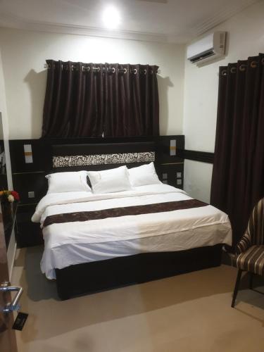 a bedroom with a large bed with black curtains at Downunder suites in Gwarinpa