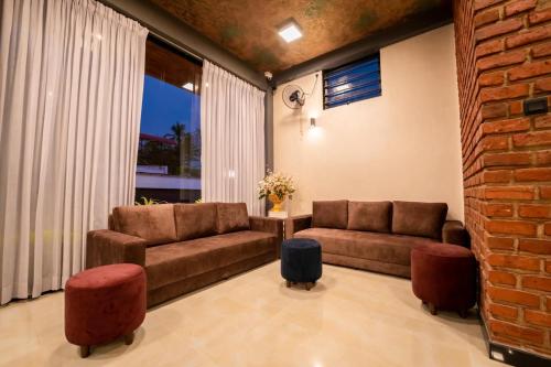 a living room with two couches and a brick wall at Limeshine - Airport Transit Hotels & Residences in Katunayake