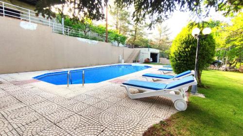 a group of lounge chairs next to a swimming pool at Fun Guest House with Pool near Troodos in Perapedhi