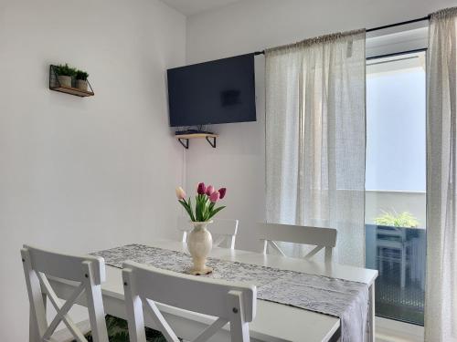 a dining room with a table with chairs and a vase of flowers at Apartments Sun & Sea in Dugi Rat