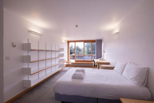 een witte slaapkamer met een bed en een raam bij Harvey Court Gonville and Caius College in Cambridge
