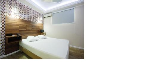 a bedroom with a white bed and a projection screen at Motel Replay Paulinia in Paulínia