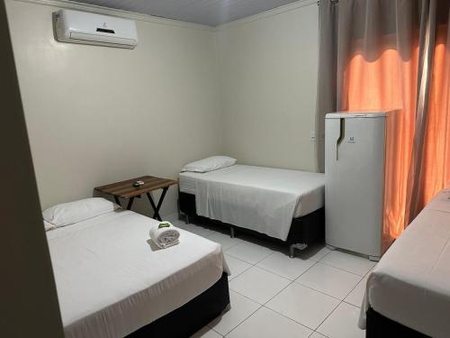Habitación de hotel con 2 camas y nevera. en PRINCIPE HOTEL, en Sorriso