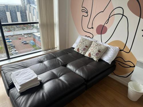 un sofá de cuero negro en una habitación con una gran ventana en Pass the Keys Cosy 1 bed next to SEC, OVO Hydro, Finnieston, en Glasgow