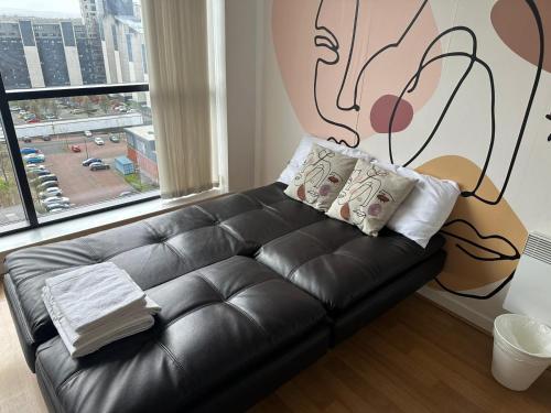 a black leather couch in a room with a large window at Cosy 1 bed next to SEC, OVO Hydro, Finnieston - Pass the Keys in Glasgow
