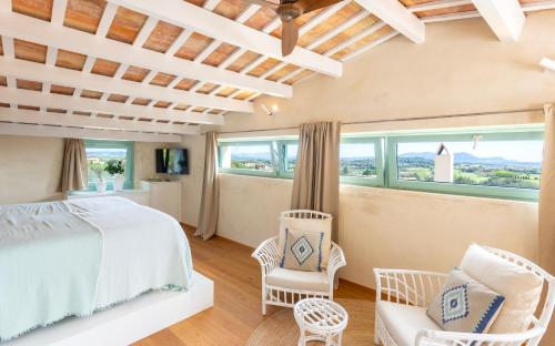 a bedroom with a bed and chairs and windows at MAS CASA GRAN in Rupiá