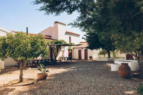 a courtyard of a house with trees and benches at Casa de campo em Venda do Duque in Vimieiro