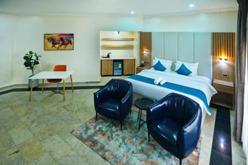 une chambre d'hôtel avec un lit et deux chaises dans l'établissement Hamasville Boutique Hotel, à Abuja
