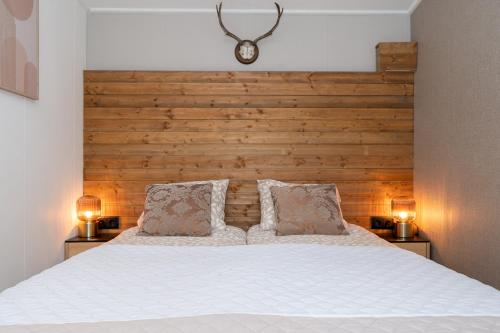 een slaapkamer met een groot wit bed met 2 lampen bij Hotel chique chalet met zicht over de weilanden op de Veluwe in Epe