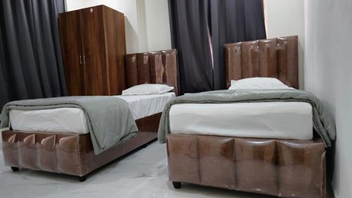 2 aparte bedden in een kamer met bruin meubilair bij Single Suite room in Hyderabad