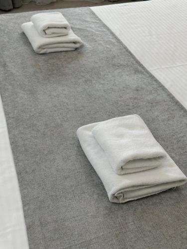 trzy białe ręczniki siedzące na dywanie w obiekcie PORT INN Hotel w mieście Astana