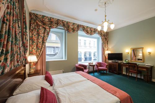 Cette chambre comprend un lit, un bureau et une fenêtre. dans l'établissement Hotel Liberty, à Prague