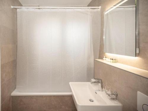 La salle de bains blanche est pourvue d'un lavabo et d'une douche. dans l'établissement Very Nice Villa i Rødbyhavn, à Rødby