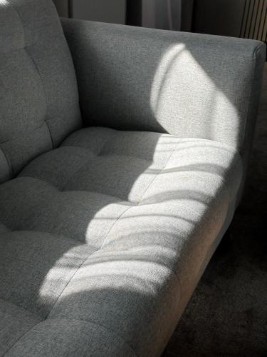 a couch sitting in a living room with the sun shining on it at PORT INN Hotel in Astana