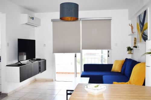 a living room with a blue couch and a table at Sunny Rooftop in Ayia Napa 91Sqm Terrace Delight! in Ayia Napa