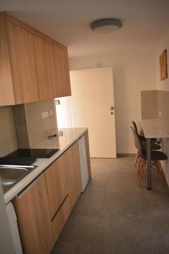 a kitchen with wooden cabinets and a table and chairs at Green Bay Suites in Protaras
