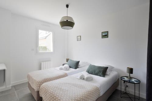 two beds in a room with white walls at La Garde & Le Repos - Proche plage St Lunaire in Saint-Lunaire