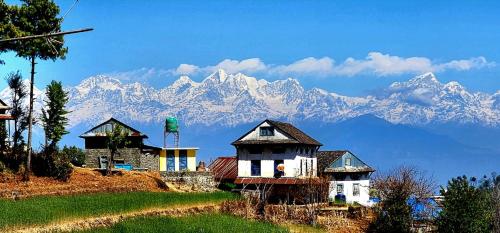 a group of houses on a hill with mountains in the background at Dhunkharka Homestay in Panaoti