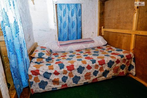 a bed with a quilt on it in a room at Dhunkharka Homestay in Panaoti