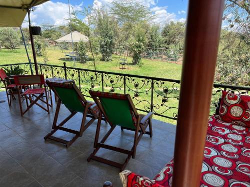 a balcony with chairs and tables and a view of a park at Nyumba ya Farasi in Naivasha