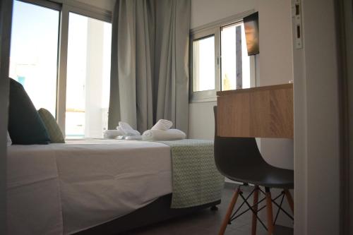 a bedroom with a bed with a chair and windows at Green Bay Suites in Protaras