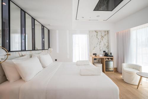 a white bedroom with a large white bed with white pillows at Ethereal White Resort Hotel & Spa - Adults Only in Heraklio Town