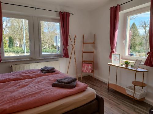 een slaapkamer met een bed met rode lakens en 2 ramen bij Eckhaus am Rödertor in Rothenburg ob der Tauber in Rothenburg ob der Tauber
