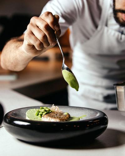 a person is eating a plate of food with a spoon at Ethereal White Resort Hotel & Spa - Adults Only in Heraklio Town