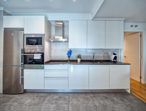 a kitchen with white cabinets and a stainless steel refrigerator at Amara Prime San Sebastian in Donostia-San Sebastián