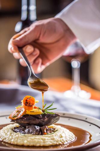 a person holding a spoon over a plate of food at Ethereal White Resort Hotel & Spa - Adults Only in Heraklio Town